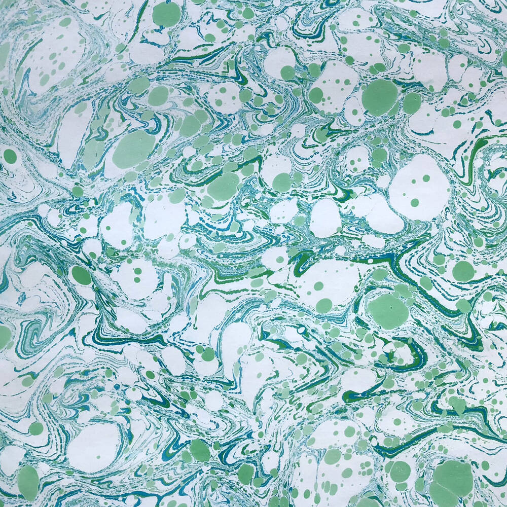 Marmorpapier / marbled paper in den Farben grün und weiss. Es ist ein durchzogenes Muster mit einzelnen grünen Flecken.